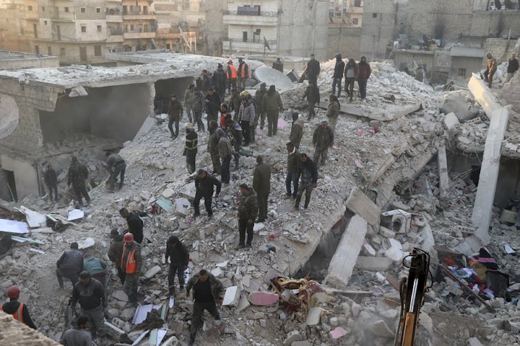 People stand on the wreckage of a collapsed five-storey building in Aleppo, Syria