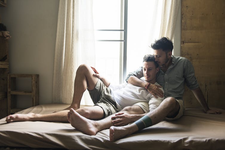 Two young men relaxed on a bed.