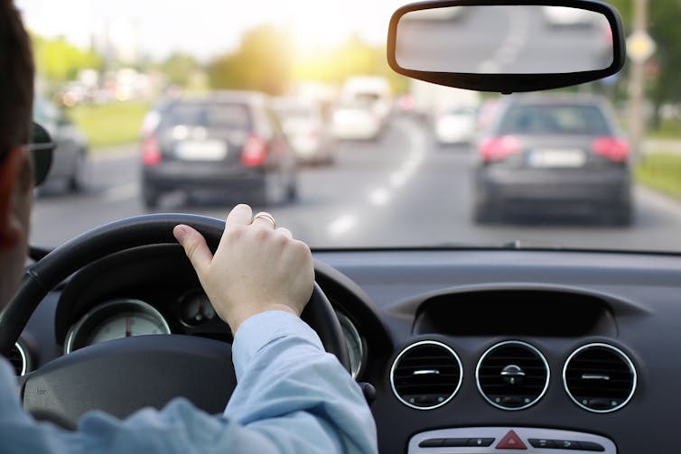 A man driving a car at rush hour.