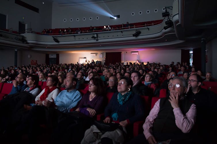 El público mira a la pantalla en una sala de cine a oscuras.