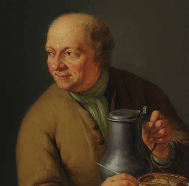 A bald man holds a large tankard of ale. 