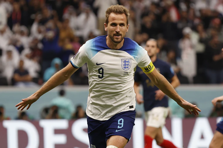 Harry Kane in his England kit. Running with arms out stretched.
