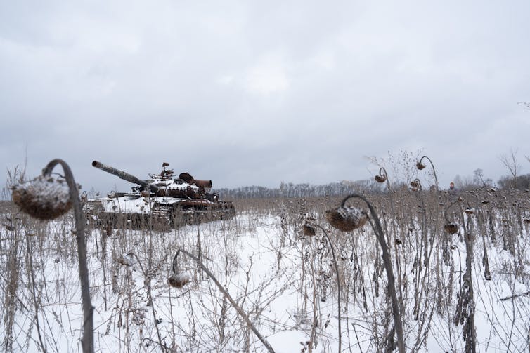 A tank in a field lightly covered with snow.