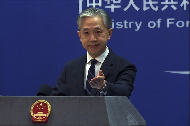 A man in a suit stands at a podium.