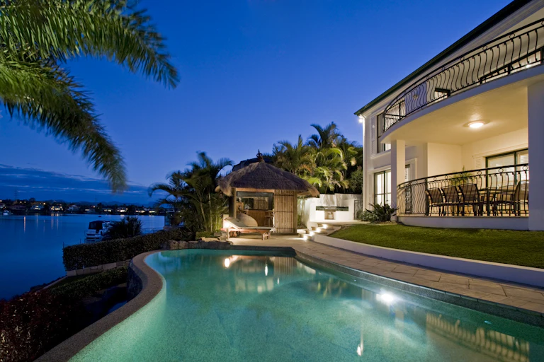 Backyard pool and entertaining area of luxury home lit up in the evening