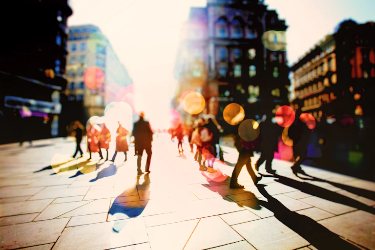 A backlit shot of blurred figures walking in a street setting.