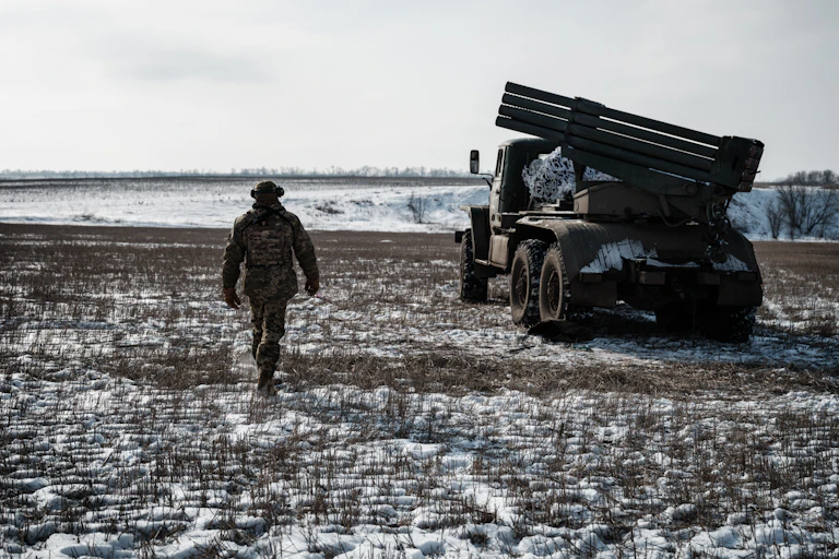 Soldat près d'un véhicule d'artillerie dans un champ enneigé.