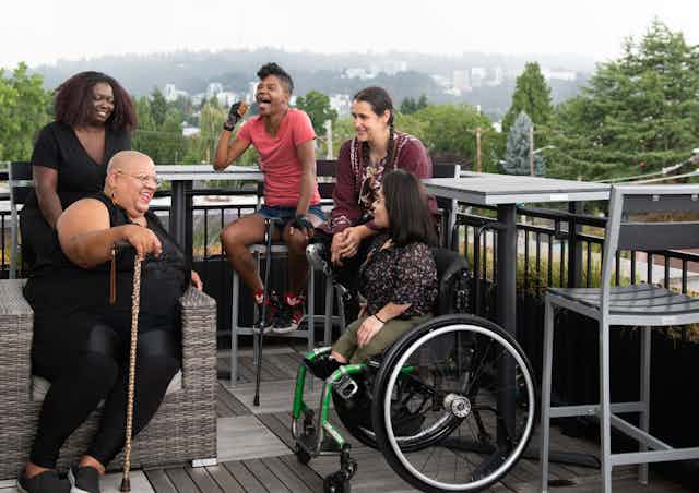 group of people on outdoor balcony. Some have mobility assistance equipment