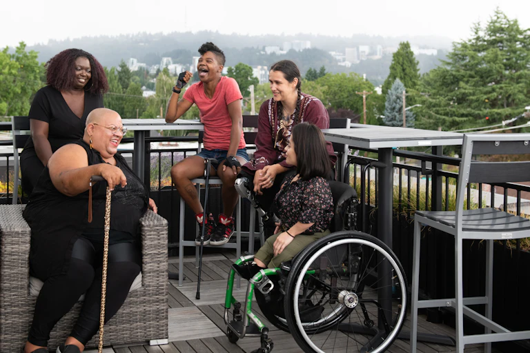 group of people on outdoor balcony. Some have mobility assistance equipment