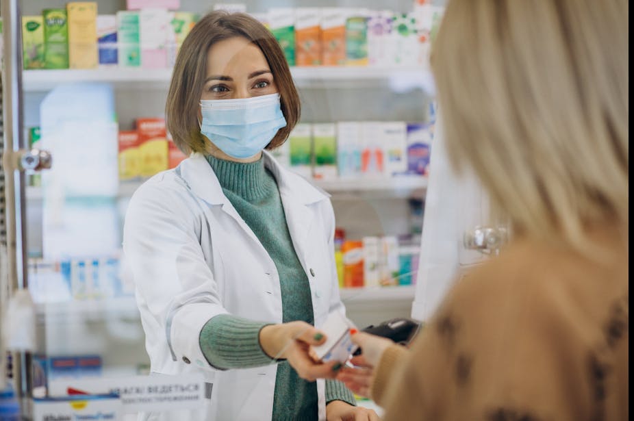 A pharmacist hands a product to a customer.