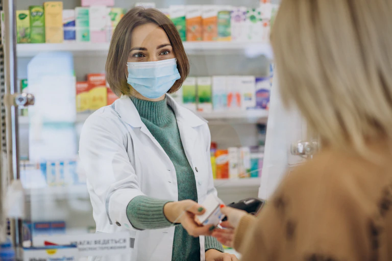 A pharmacist hands a product to a customer.