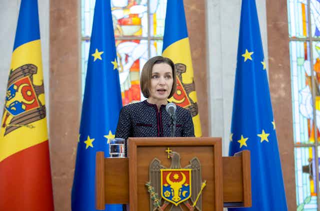 Moldovan president Maia Sandu.speaks from a rostrum in front of Moldovan and EU flags.