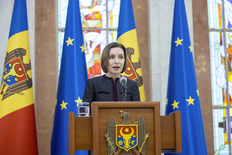 Moldovan president Maia Sandu.speaks from a rostrum in front of Moldovan and EU flags.
