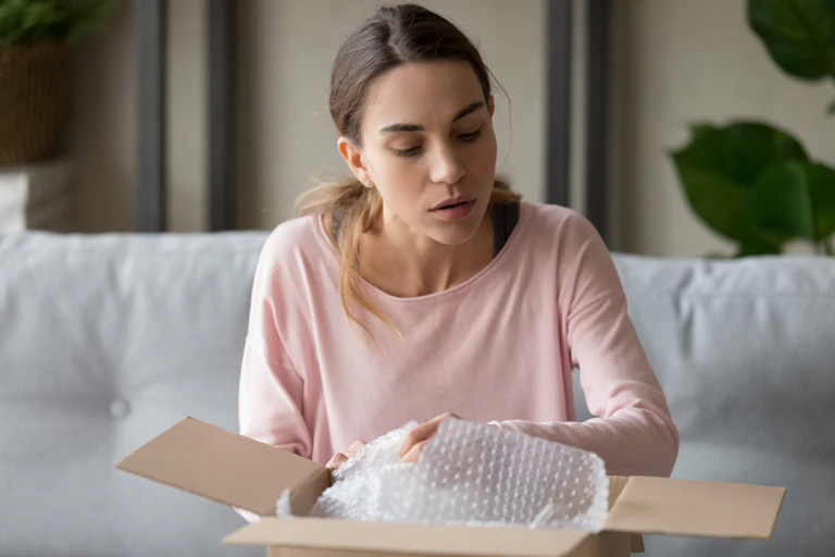 A young woman opens a cardboard box.