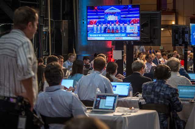 A roomful of journalists watches the 20202 Democratic Party presidential debate