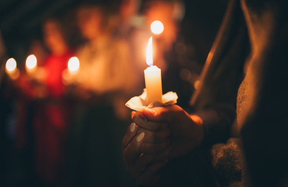 Close up photo of a woman holding a lit candle at a vigil