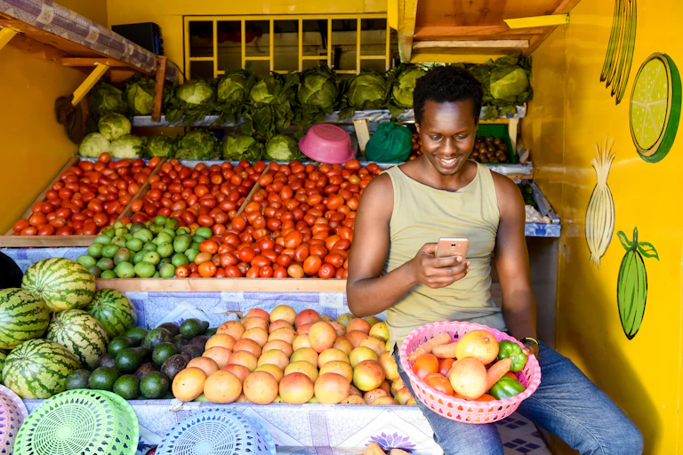Un homme se tient devant un étal de fruits.