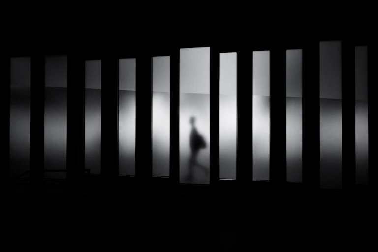 Une silhouette floue se déplace dans une image fragmentée, en noir et blanc