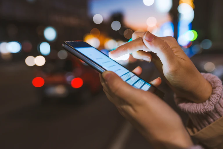 A pair of hands using a cellphone touch screen