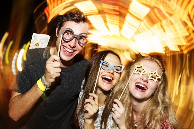 Three adults laughing and smiling at the camera.