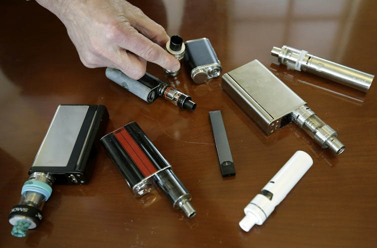 A high school principal displays vaping devices that were confiscated from students in such places as restrooms or hallways at the school in Massachusetts