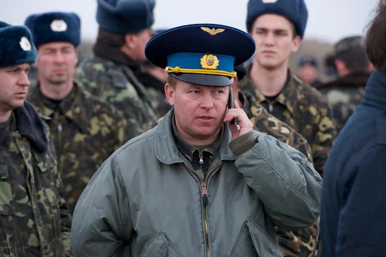 Four soldiers wearing hats and an officer looking at the camera.