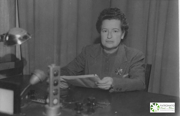 Una mujer en un estudio de radio de los años 40 mirando a cámara.