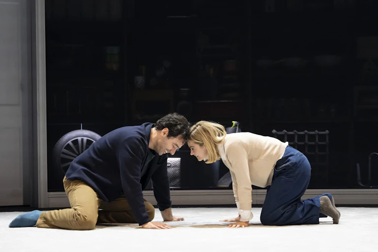 Two people on all fours touch heads.