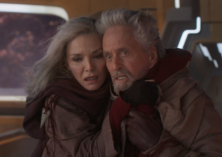 Michelle Pfeiffer and Michael Douglas both hugging in red suits, looking afraid.