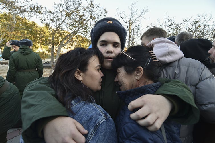 A Russian soldier holds two earful female relatives