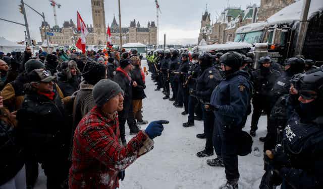 Convoy protestors face off with police in front of the Canadian parliament.