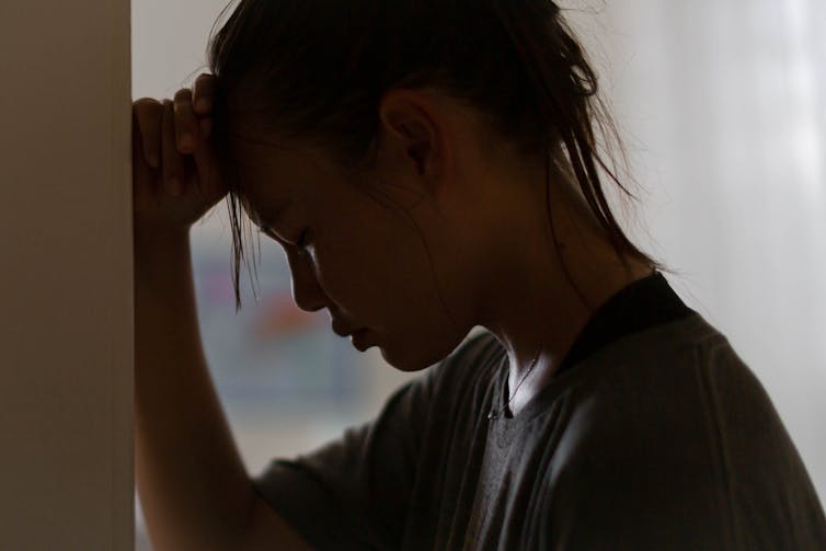 A worried young woman in profile stressed out and unhappy.