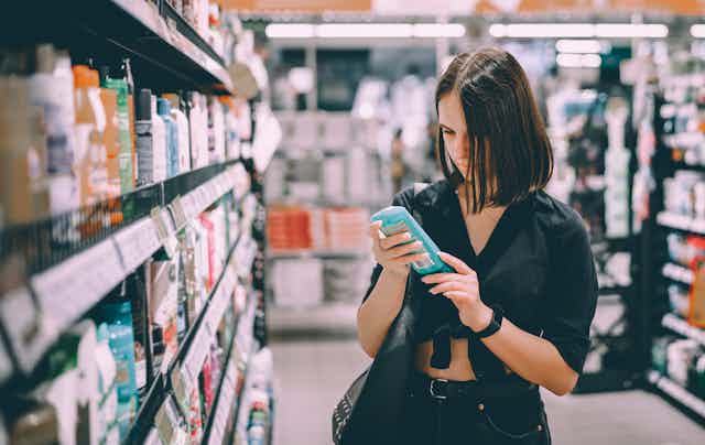 A person looks at a shampoo bottle in a shop.