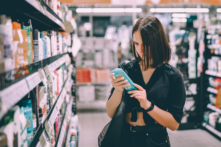 A person looks at a shampoo bottle in a shop.