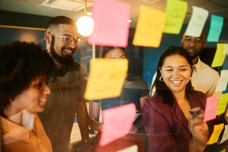 young professionals looking at glass wall with post-it notes