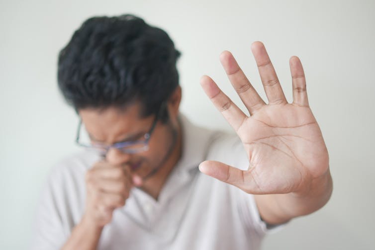 Man coughing, holding his hand up