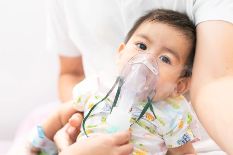 Toddler in father's arms being treated for respiratory illness with mask