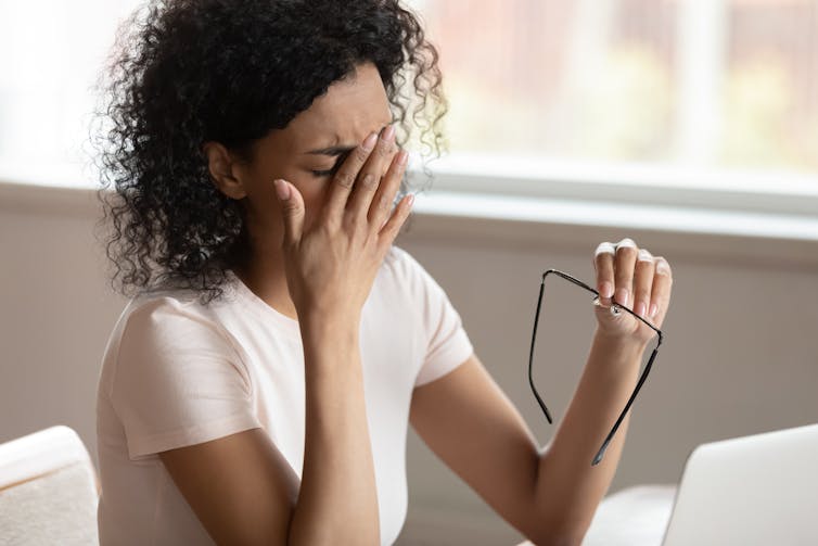 Woman rubbing face at desk