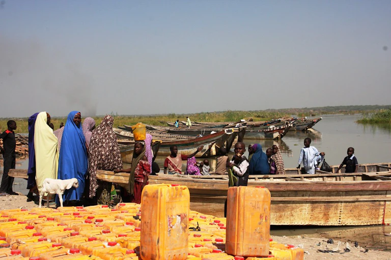 A group of women waiting by a lake for boats