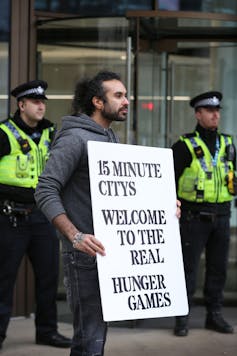 Man holds 15 minute cities placard