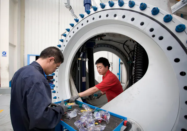 Two workmen in China making a wind turbine