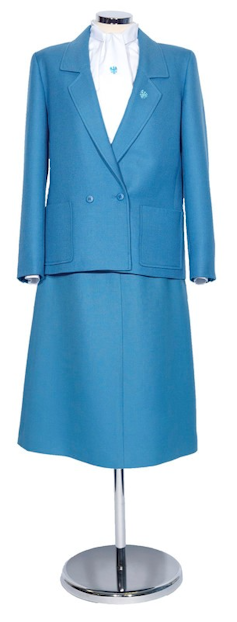 Blue two-piece skirt suit with white shirt and Barclays logo on bow and lapel, on a stand.