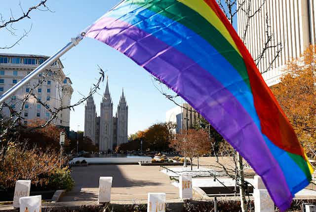 A rainbow flag flies down the street from a large cathedral.