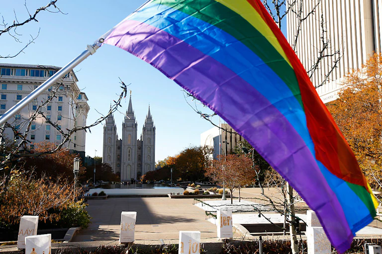A rainbow flag flies down the street from a large cathedral.