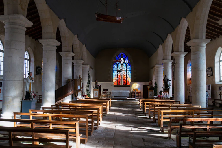 View of a church altar and pillars with empty wooden pews, taken from the back of a sanctuary.