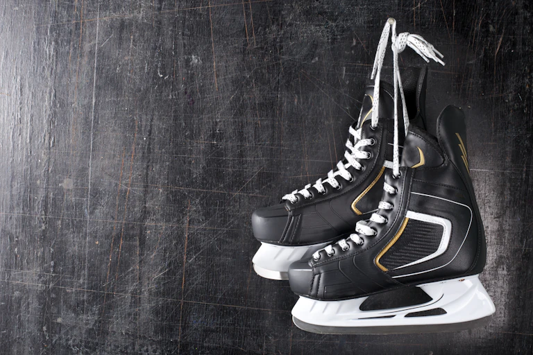 A pair of black hockey skates hang on a hook