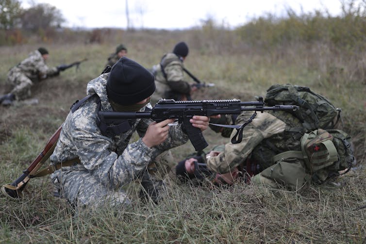 Russian soldiers aim guns in a field
