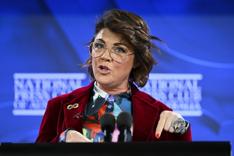 woman with glasses speaking at lectern