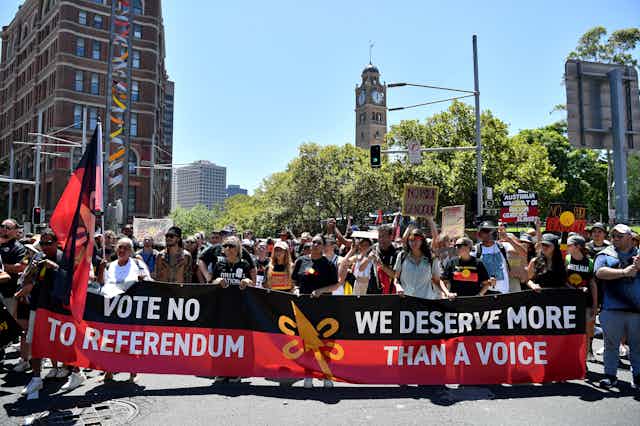 Protestors hold placards as they march through the CBD during an Invasion Day rally in Sydney.