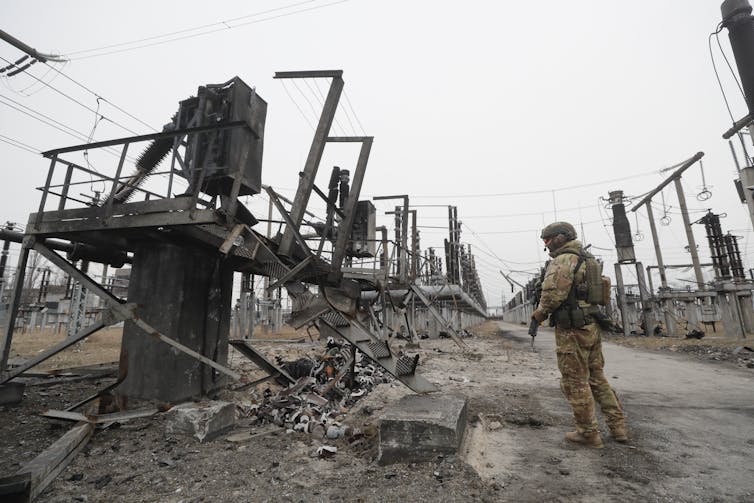 A Ukrainian soldier keeping watch at a damaged energy facility near Kyiv, February 2023.
